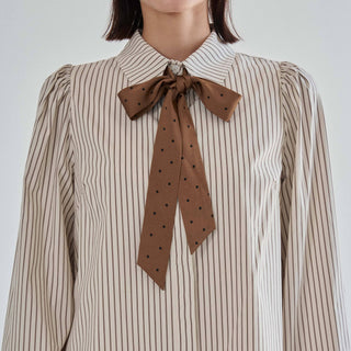 Close-up of the brown polka dot satin bow tie and pointed collar on the Marguerite striped shirt dress